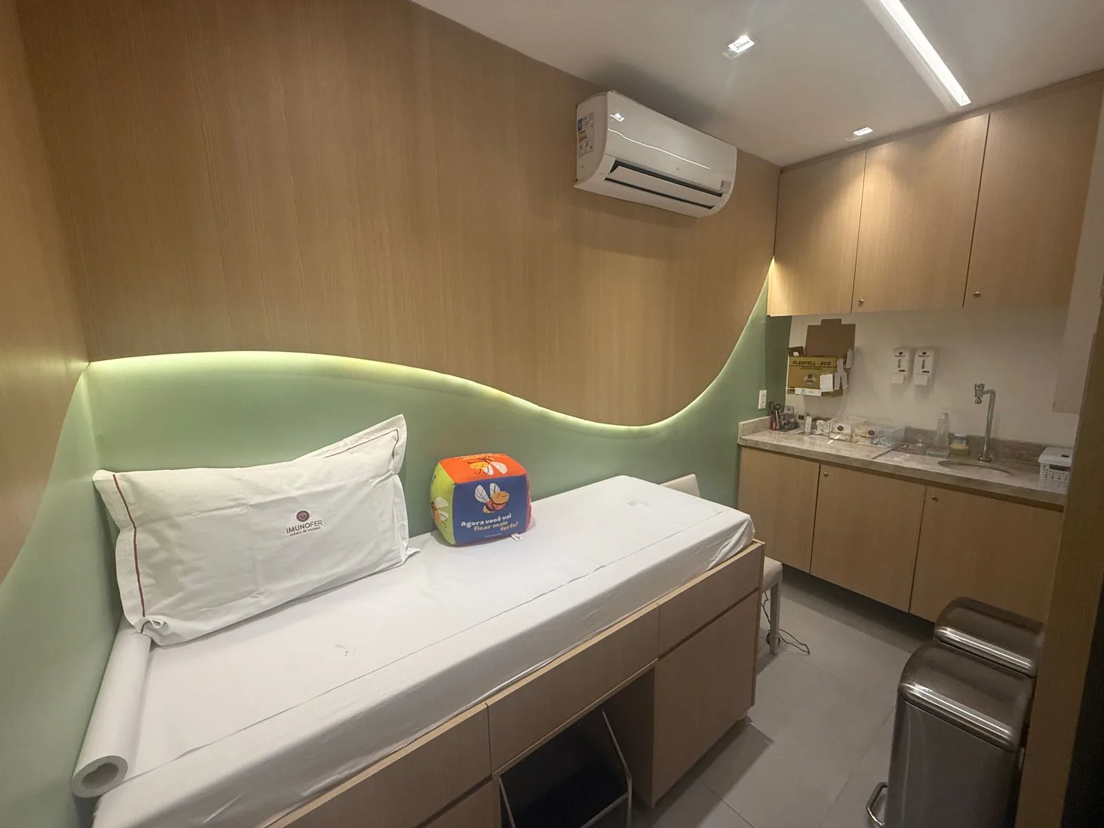 Sala de vacinação da Imunofer em Maceió, com maca, travesseiro com a marca e iluminação suave